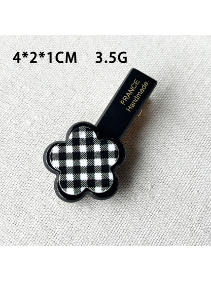 Beau acrylic hair clip shown clipped in brown hair with flower and heart accents