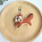 Keypus squirrel charm keychain displayed on a rustic wooden table