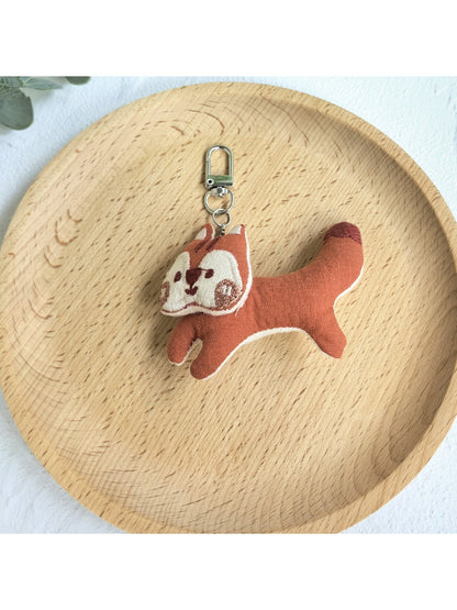 Keypus squirrel charm keychain displayed on a rustic wooden table
