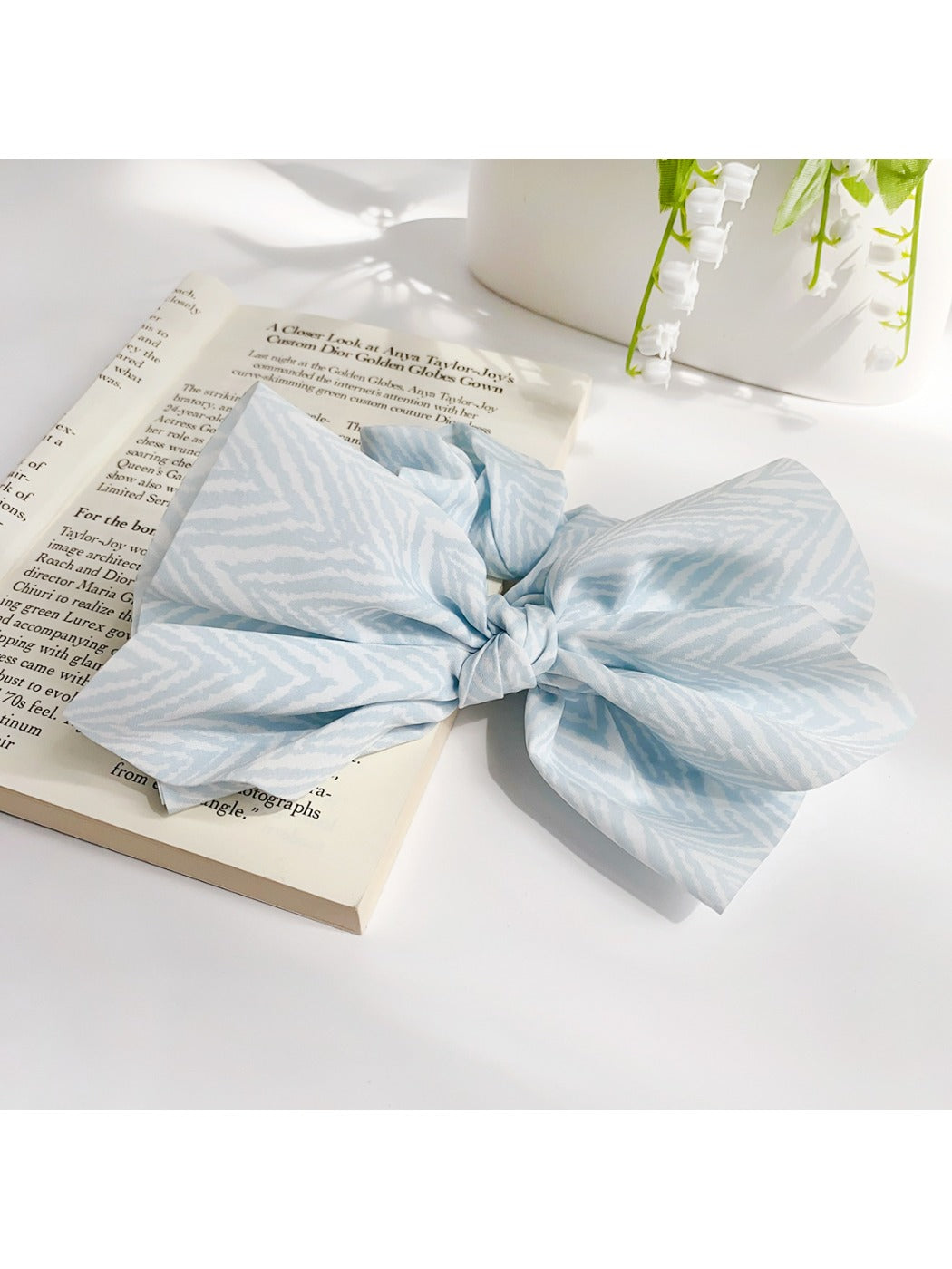 Striped bow scrunchie displayed flat showing fabric texture and pattern