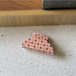 Beau polka dot claw clip resting on a wooden surface