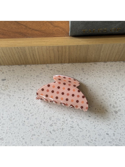 Beau polka dot claw clip resting on a wooden surface
