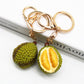 Durian shaped keychain attached to a silver keyring on a white background