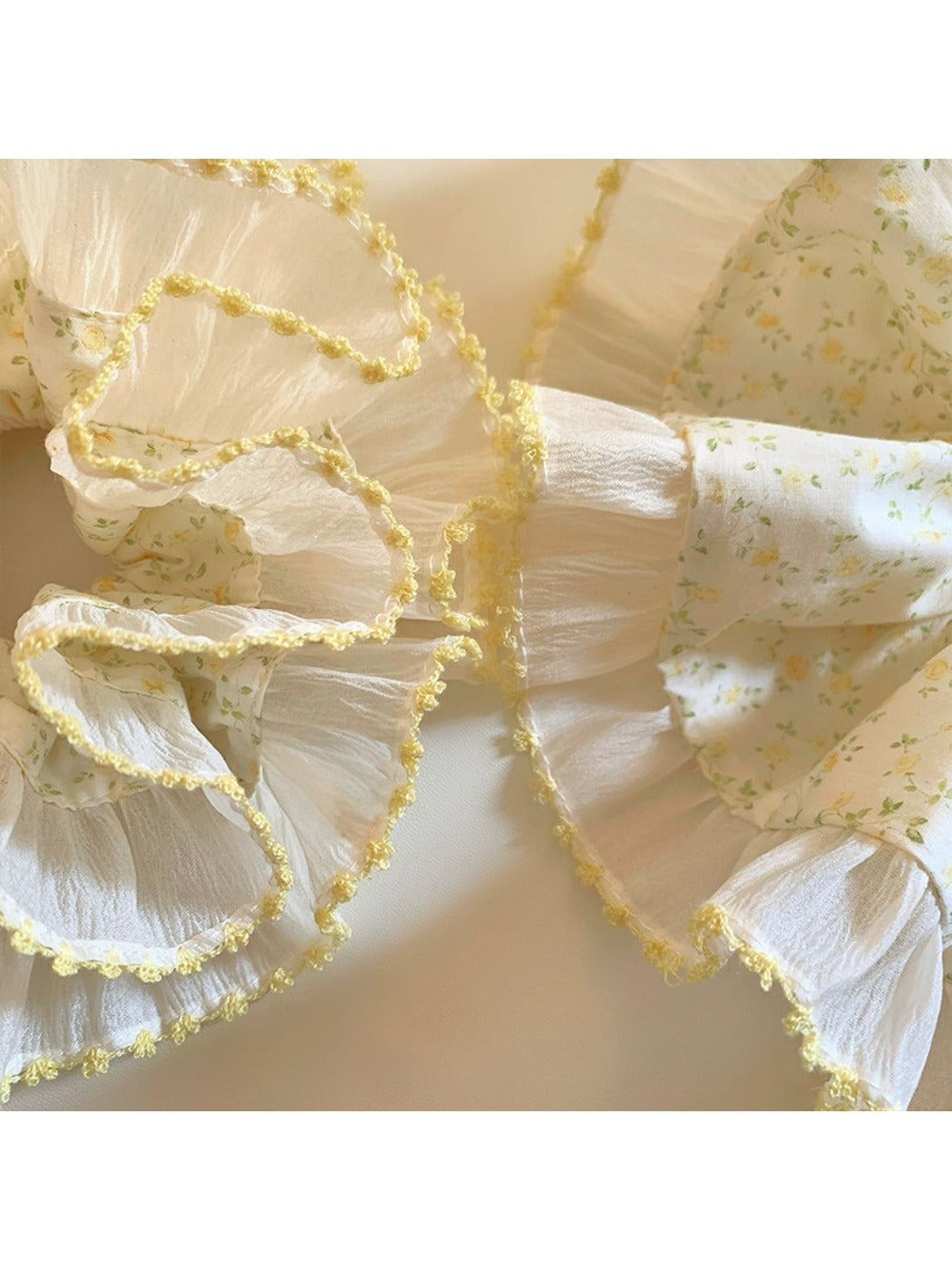 Side view of yellow pleated scrunchie showing texture and print