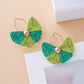 Earrings laid flat showing fan shape and natural raffia material