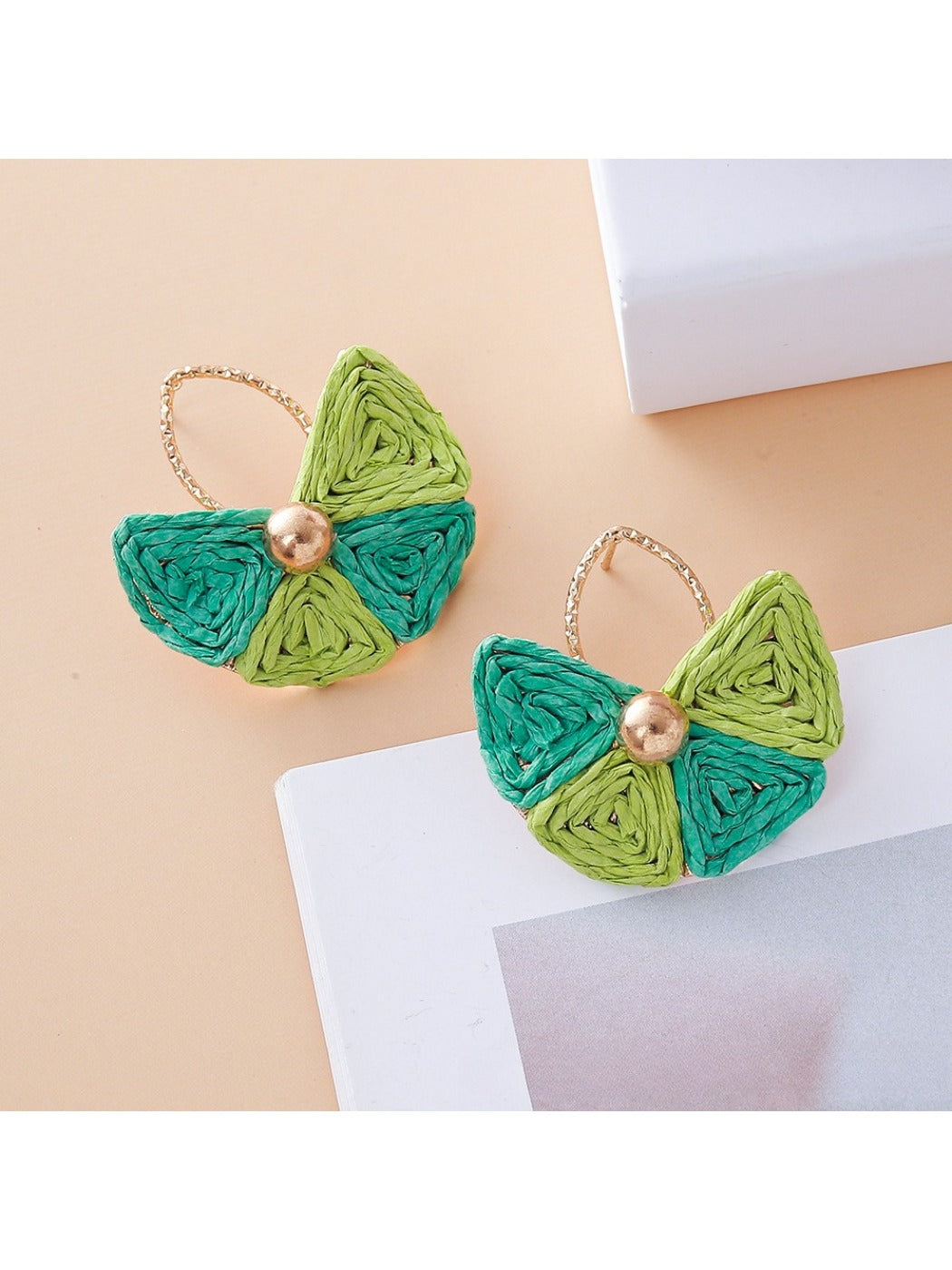 Earrings laid flat showing fan shape and natural raffia material