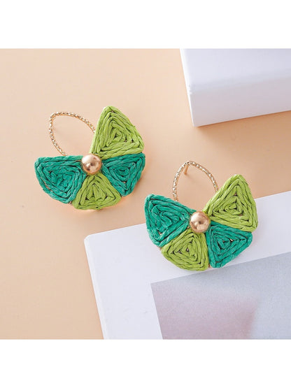 Earrings laid flat showing fan shape and natural raffia material