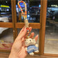 Cat charm keychain displayed on a black leather wallet