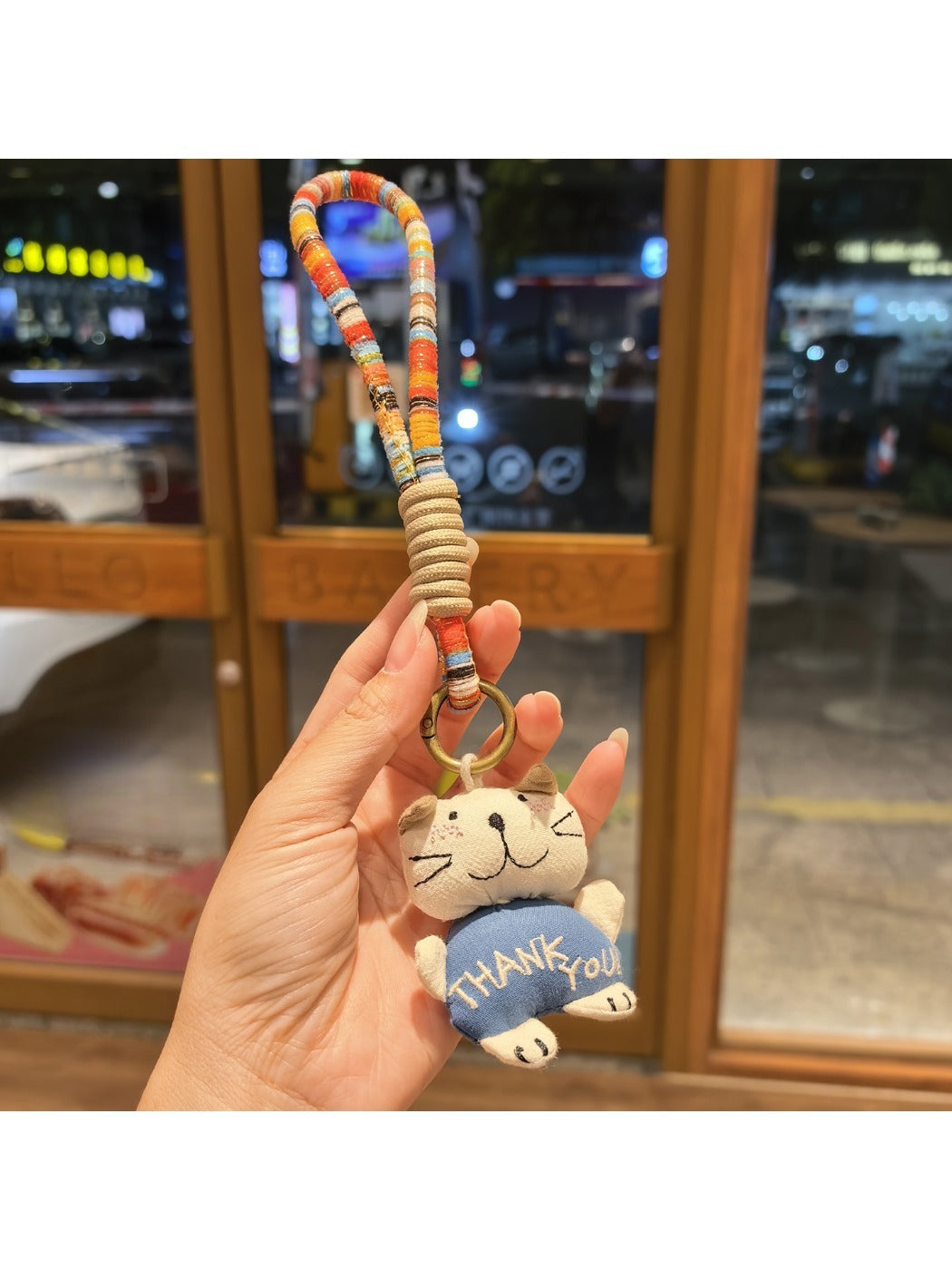 Cat charm keychain displayed on a black leather wallet