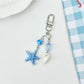 Starfish pendant keychain next to a seashell for size comparison