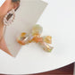 Beau delicate bow hair claw clip displayed with soft shadows on white surface