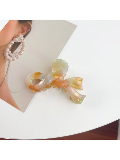 Beau delicate bow hair claw clip displayed with soft shadows on white surface