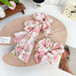 Side view of Gifty bow accented floral scrunchie highlighting fabric texture and ruffles