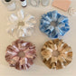 Gifty satin ruffle scrunchie displayed on a wooden surface showing texture and shine