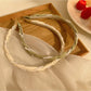 Top view of gold wire headband adorned with evenly spaced small white beads