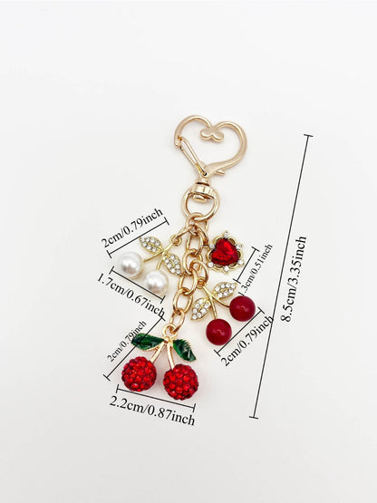 Keypus cherry charm keychain hanging from a handbag zipper pull