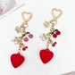 Close-up of cherry heart charm keychain showing detailed red enamel and gold edges
