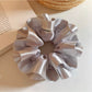 Close-up of silver satin ruffle scrunchie showing fabric texture