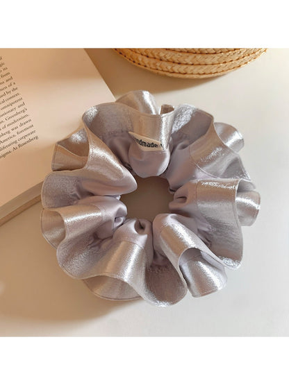 Close-up of silver satin ruffle scrunchie showing fabric texture
