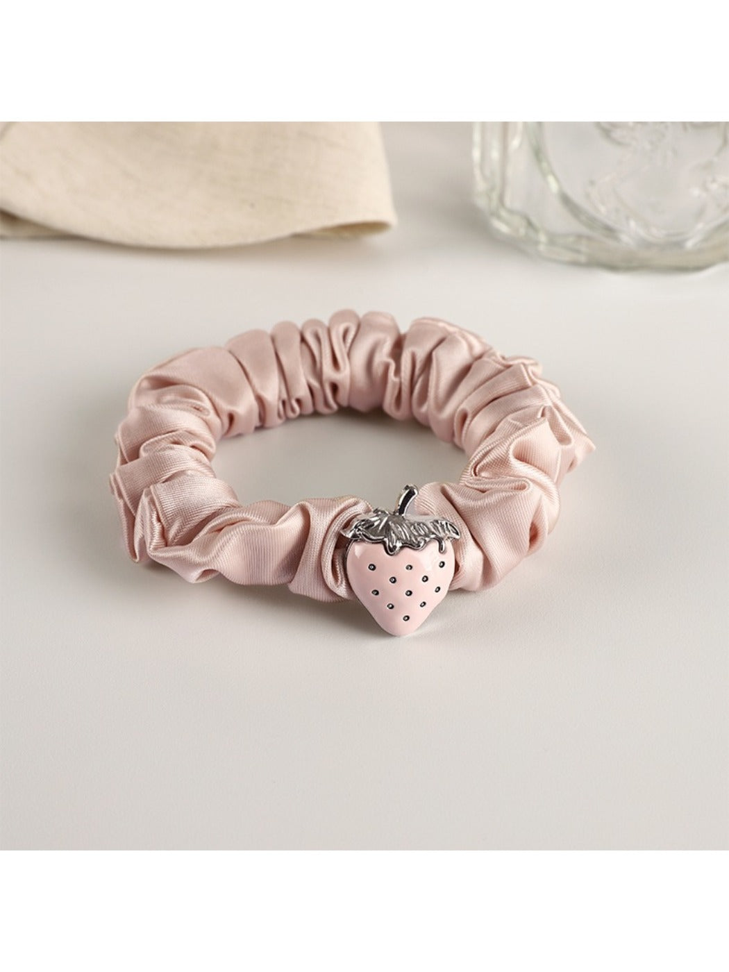 Strawberry hair tie styled with casual outfit on a wooden surface