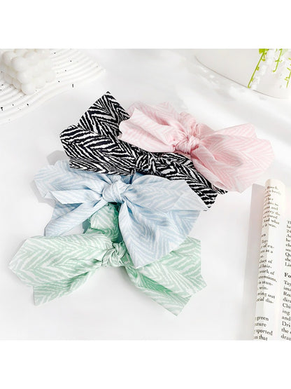 Striped bow scrunchie wrapped around a ponytail on a model with brown hair