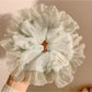 Mint green mesh scrunchie with white polka dots on a white background