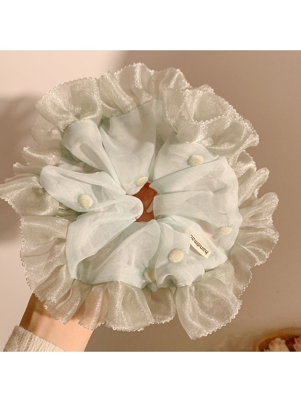Mint green mesh scrunchie with white polka dots on a white background