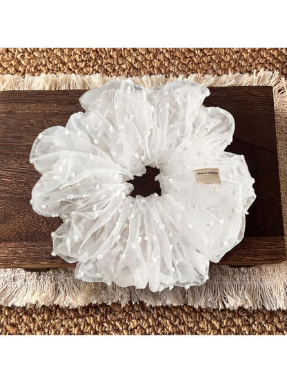 White polka dot tulle scrunchie packaged in a clear plastic bag