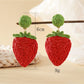 Side view of raffia woven strawberry earrings showing texture and weave