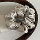 Gifty ruffled satin scrunchie styled in a ponytail on a model with dark hair