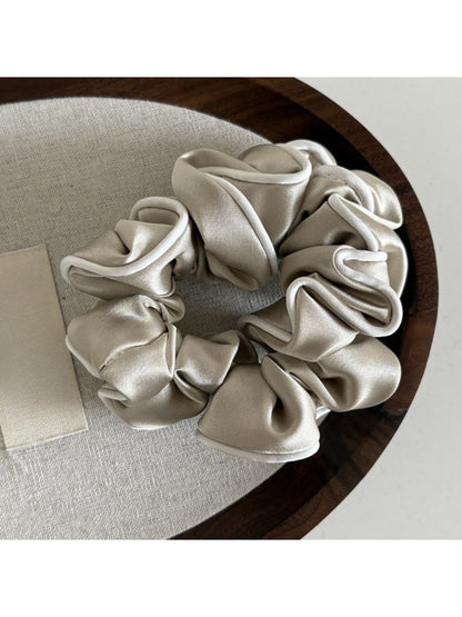Gifty ruffled satin scrunchie styled in a ponytail on a model with dark hair