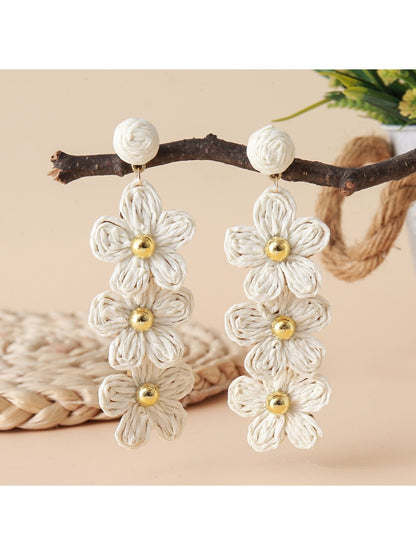 Detailed view of raffia fibers woven into flower shape on drop earrings