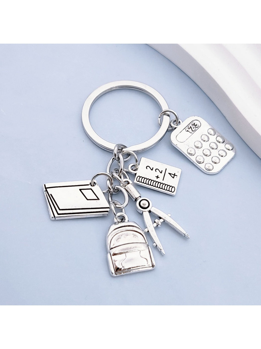 Close-up of the book-shaped alloy backpack keychain showing detailed texture