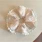 Close-up of Gifty satin scrunchie with pink bow print on white background