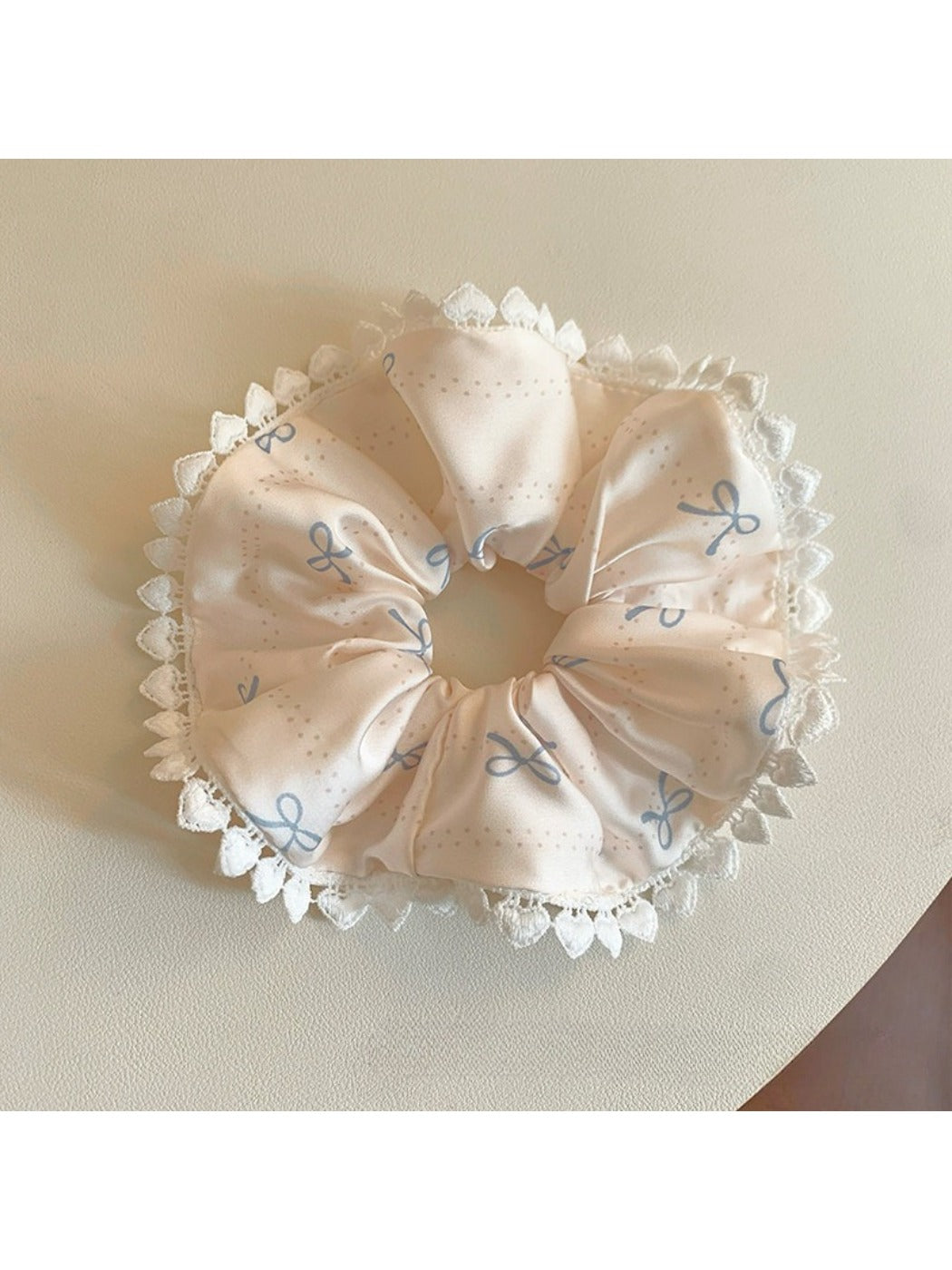 Close-up of Gifty satin scrunchie with pink bow print on white background