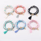 Close-up of Lovra stackable tassel beaded bracelet with multicolored beads and gold accents