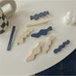 Side view of Beau hair clip highlighting the curved shape and blue floral details