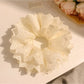 Elegant white fluffy scrunchie with layered ruffles on a plain background