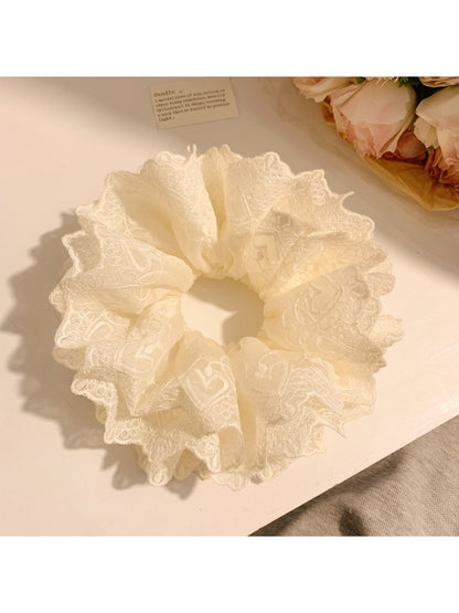 Elegant white fluffy scrunchie with layered ruffles on a plain background