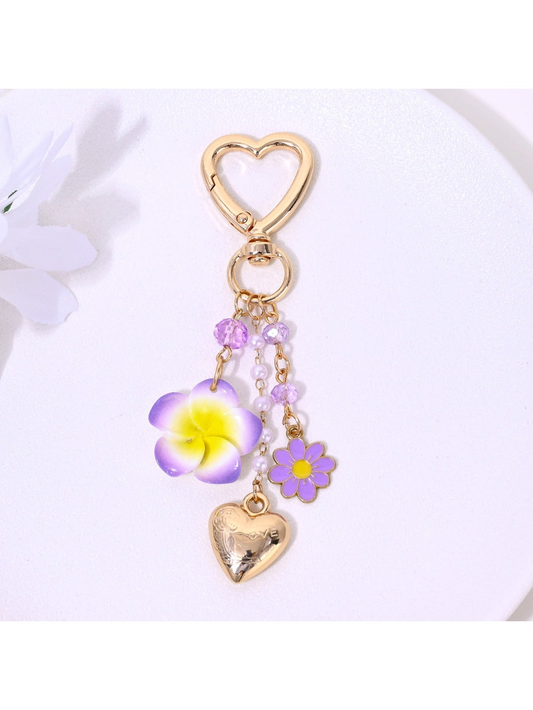 Gold keychain with heart and flower charms hanging from a hook