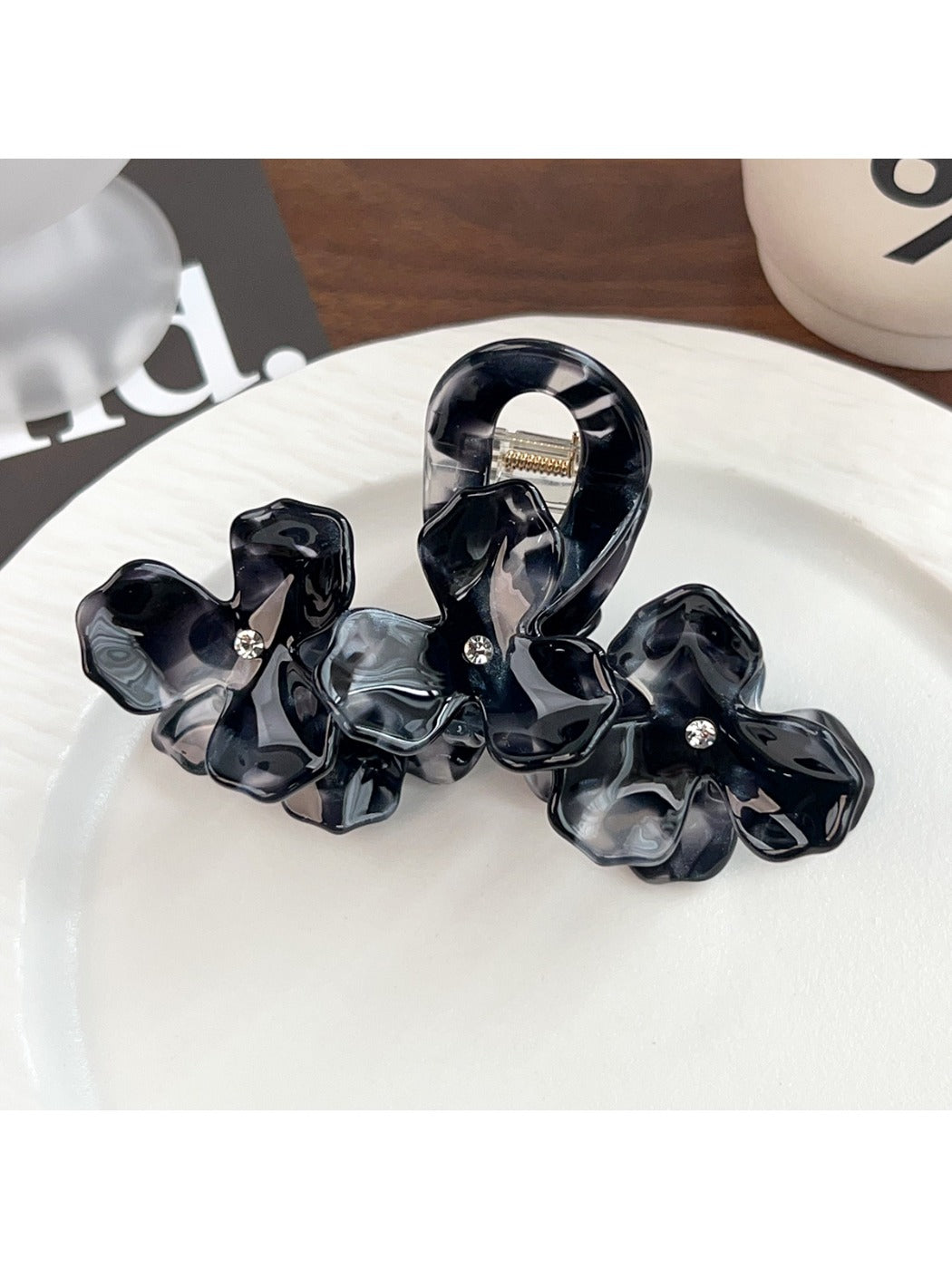 Beau hair claw clip held in hand showing size and intricate floral pattern
