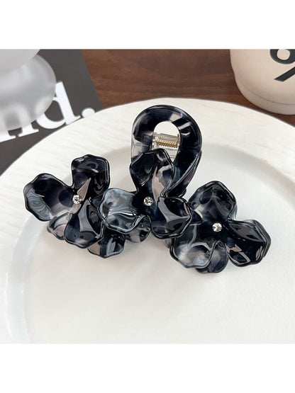 Beau hair claw clip held in hand showing size and intricate floral pattern