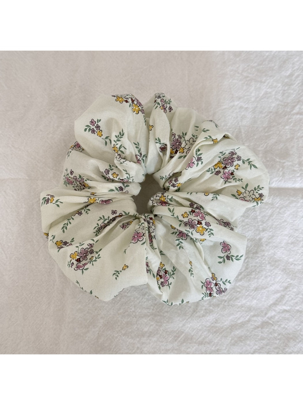 Hand holding the Gifty Sweet Green Style Scrunchie showing its stretch and texture
