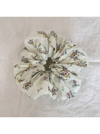 Hand holding the Gifty Sweet Green Style Scrunchie showing its stretch and texture