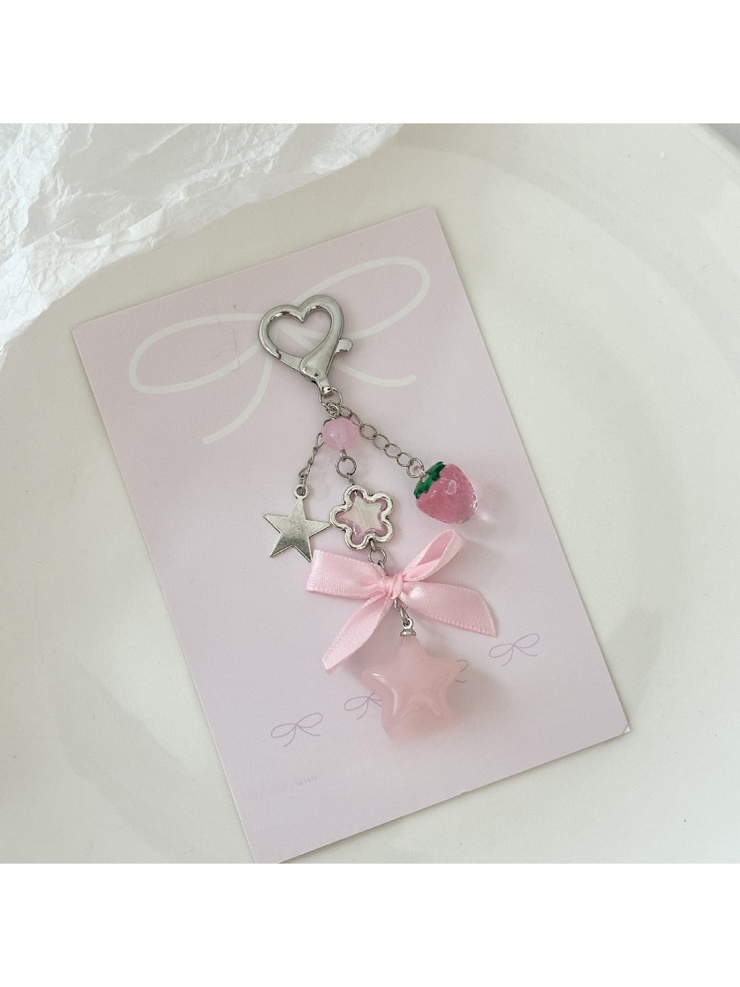 Pink star keychain hanging from a set of keys on a white background