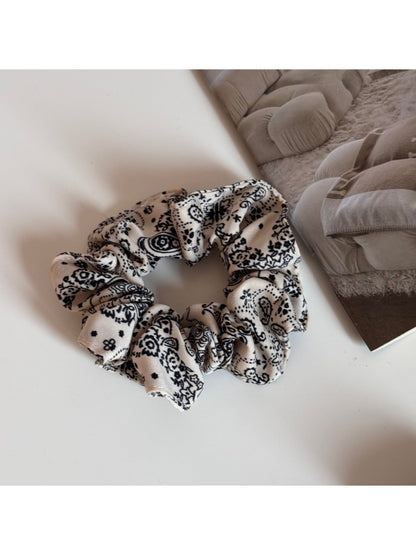 Gifty scrunchie worn on a wrist as a stylish accessory with artistic print
