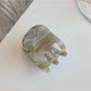 Beau hair clip photographed with soft shadows highlighting glossy texture