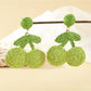 Earrings placed on a wooden surface highlighting natural raffia material