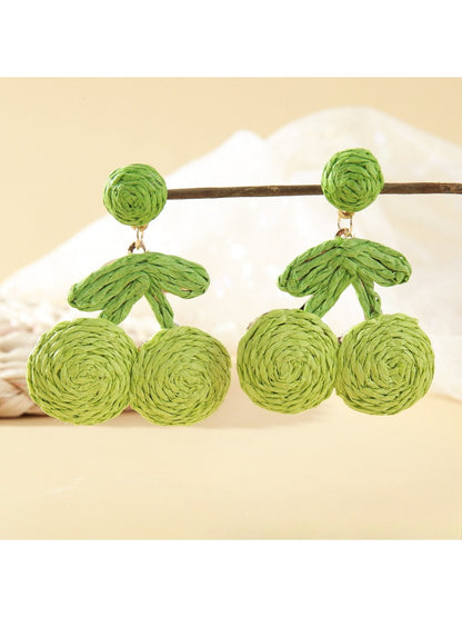 Earrings placed on a wooden surface highlighting natural raffia material
