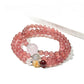 Lovra triple wrap bracelet with pink crystal beads and gold accents on a white background